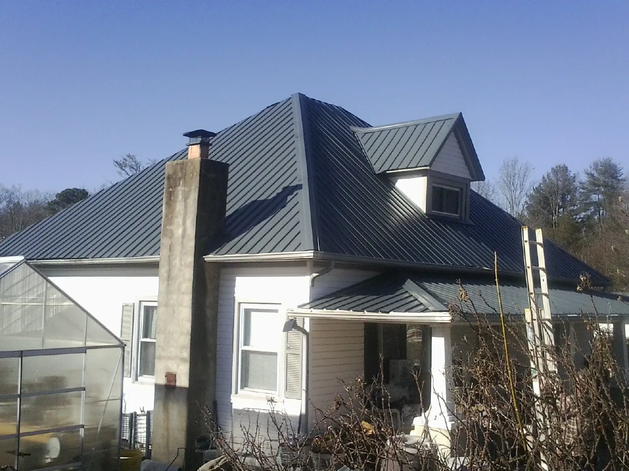 Dark blue standing seam metal roof on a white farmhouse with dormer — Slate & Tile Roof Repair by Roofing Brothers in Mountain Home Afb