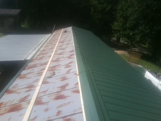 Old rusted panels beside newly installed green metal roofing — Wind Damage Roof Repair by Roofing Brothers in Mountain Home Afb