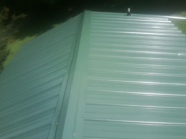 New green metal panels meeting at the ridge of a roof — Flat Roof Repair work by our crew in Mountain Home Afb