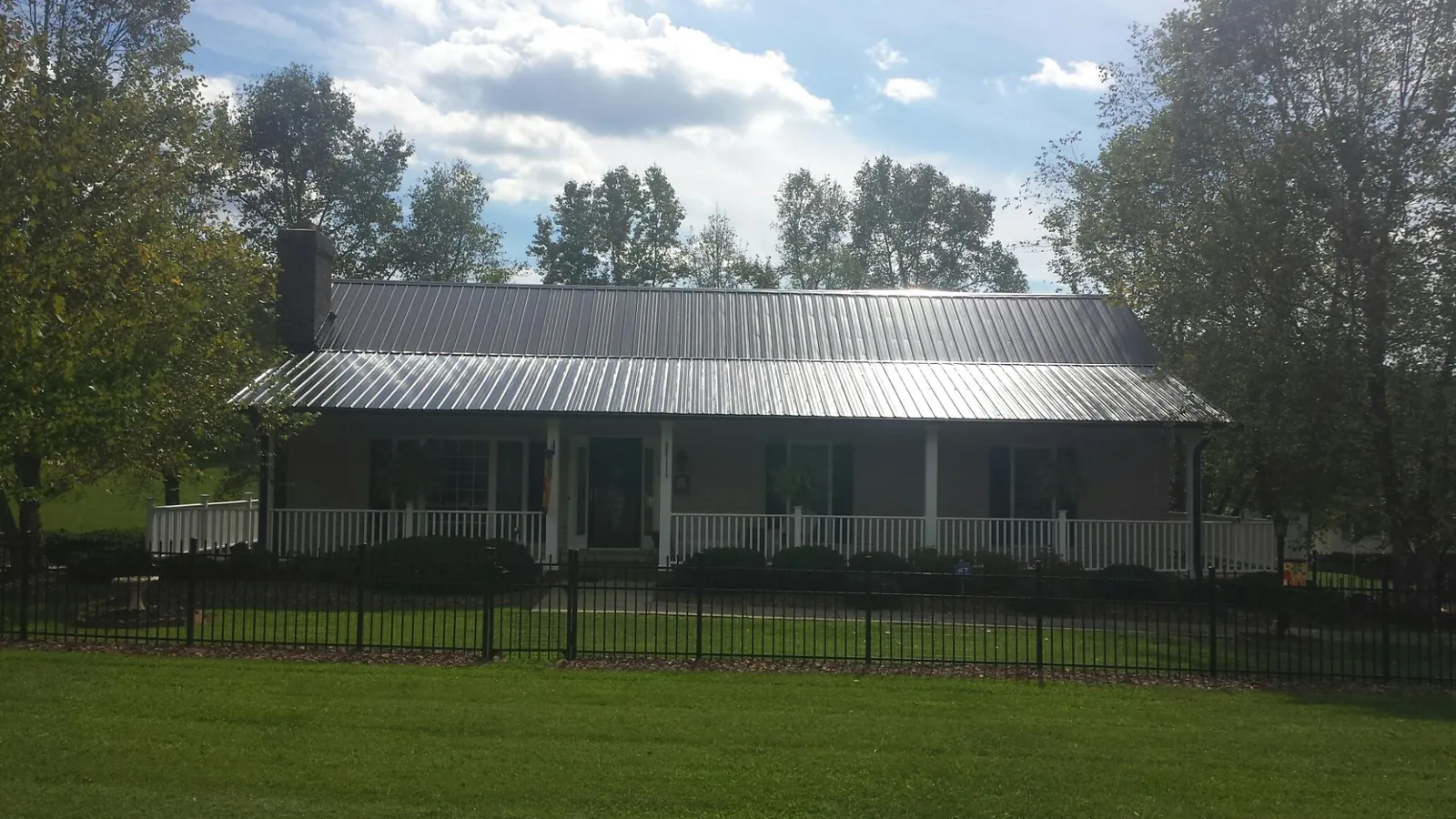 Gray metal roof on a brick ranch with a full width front porch — Gutter Guard Installation work by our crew in Mountain Home Afb
