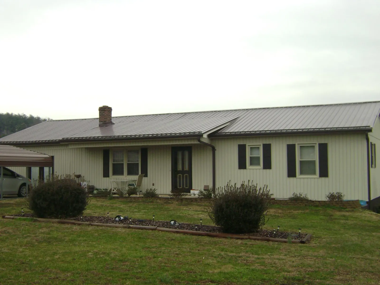 Brown metal roof on a cream sided ranch home with a brick chimney in Mountain Home Afb