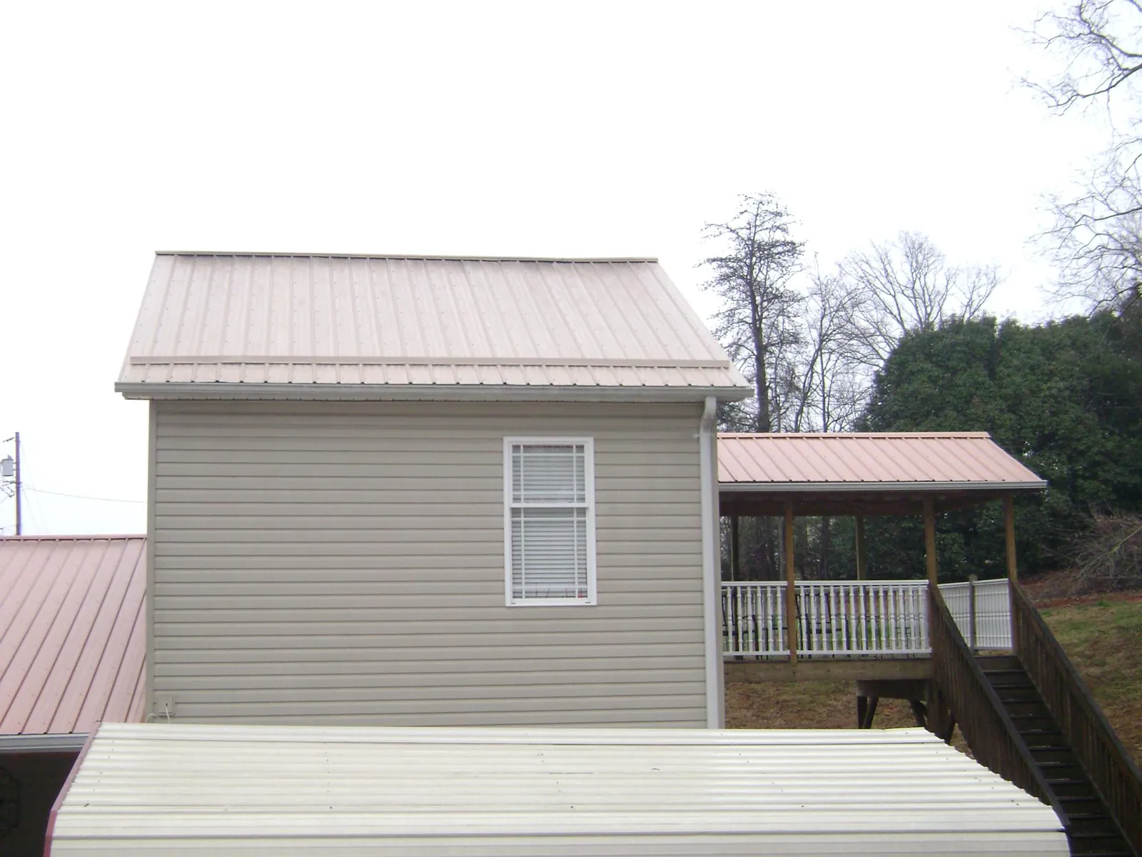 Tan metal roofs on a two story addition and attached porch, from a Roof Replacement job in Mountain Home Afb
