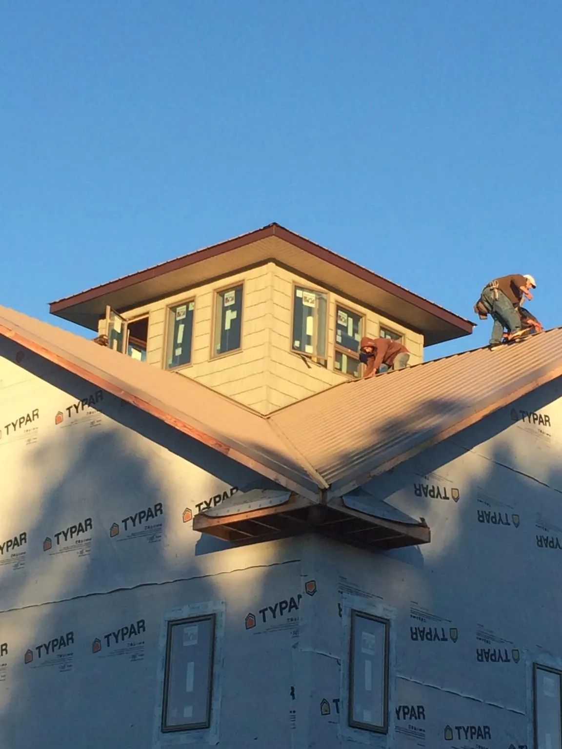 Roofers working around a rooftop cupola on a new metal roof at sunset — Roof Waterproofing in Mountain Home Afb by Roofing Brothers